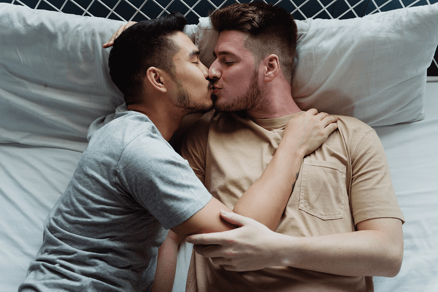 two men kissing in bed